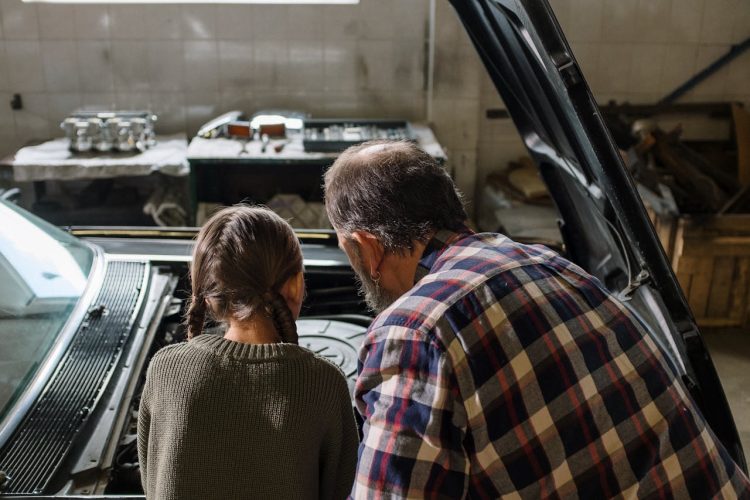 back-view-of-a-dad-and-his-daughter-looking-under-the-car-hood