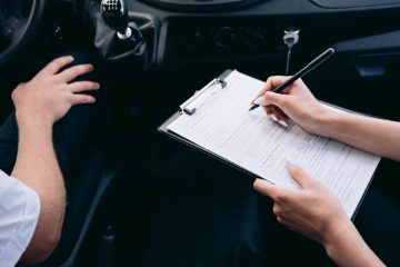 person-writing-on-a-clipboard-inside-the-vehicle